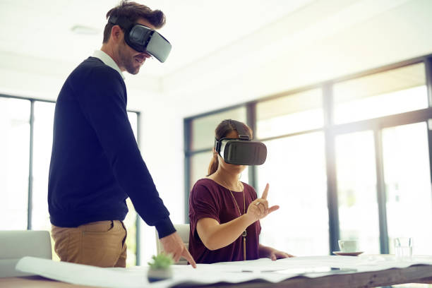 Shot of two businesspeople wearing VR headsets while working together in an office