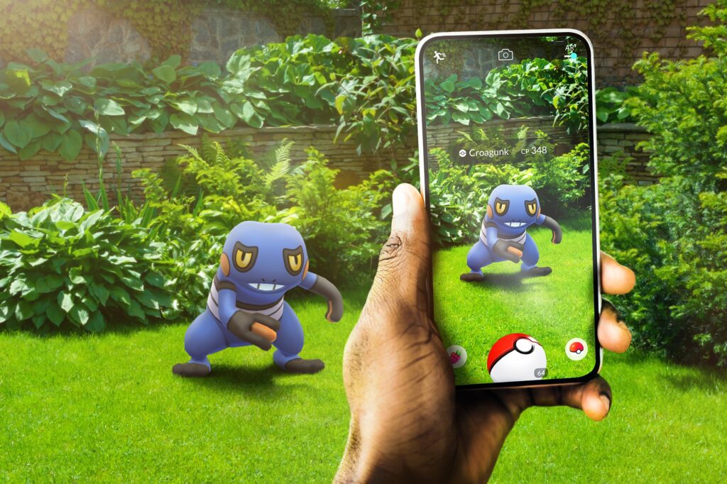 A person holding up their smartphone with Pokémon GO loaded, featuring a Pokémon in the wild.